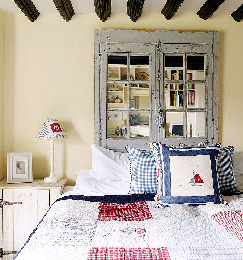 Patchwork-Quilt auf einem Bett mit geborgenem Fensterkopfteil Forest Row Bauernhaus Surrey England UK