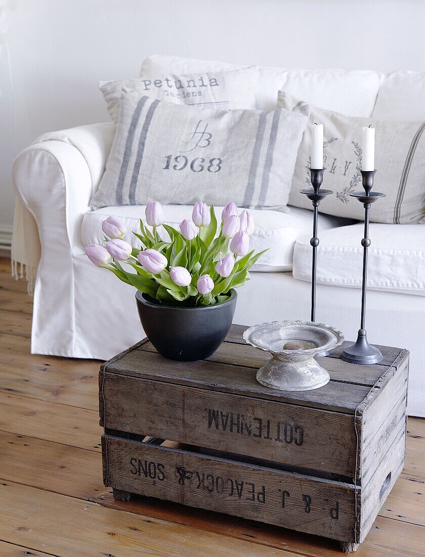 Tulips on crate with sofa and cushions in living room City of Bath Somerset, England, UK