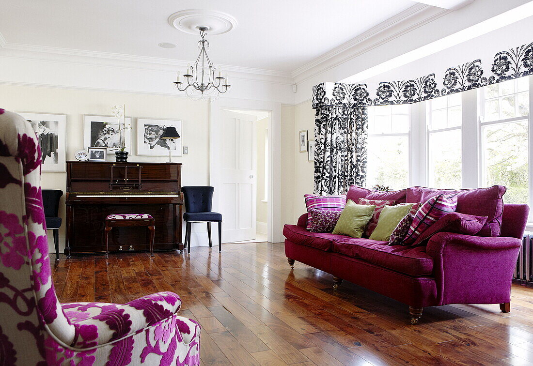 Pink sofa and piano on music room with polished wooden floor in Harrogate home Yorkshire England UK