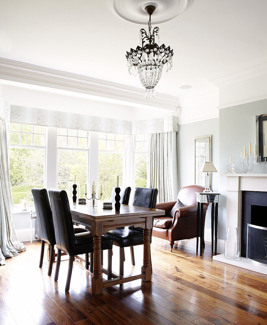 Black leather chairs at table in dining room with polished wooden floor in Harrogate home Yorkshire England UK