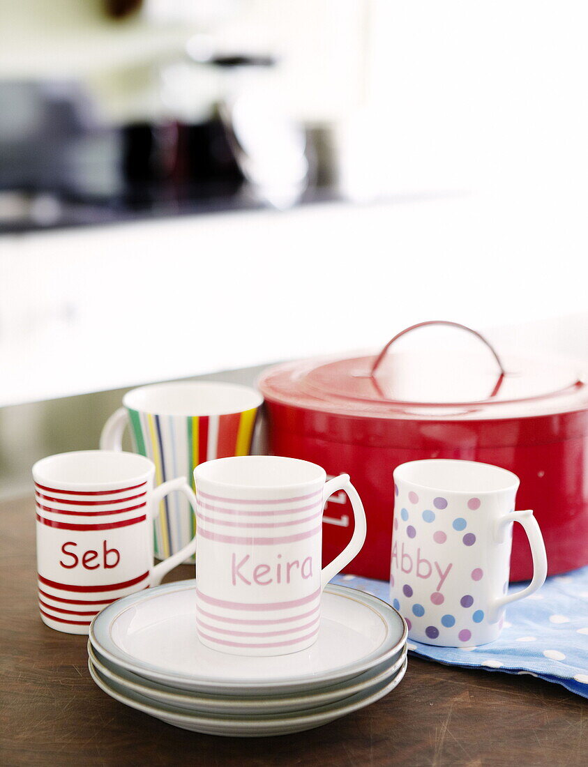 Cups with names and biscuit tin on worktop in Harrogate kitchen Yorkshire England UK