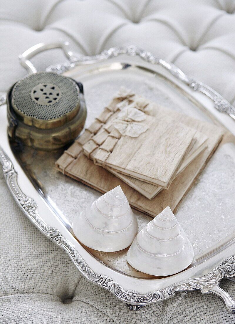 Seashells and bound notebooks on silver tray in London home UK