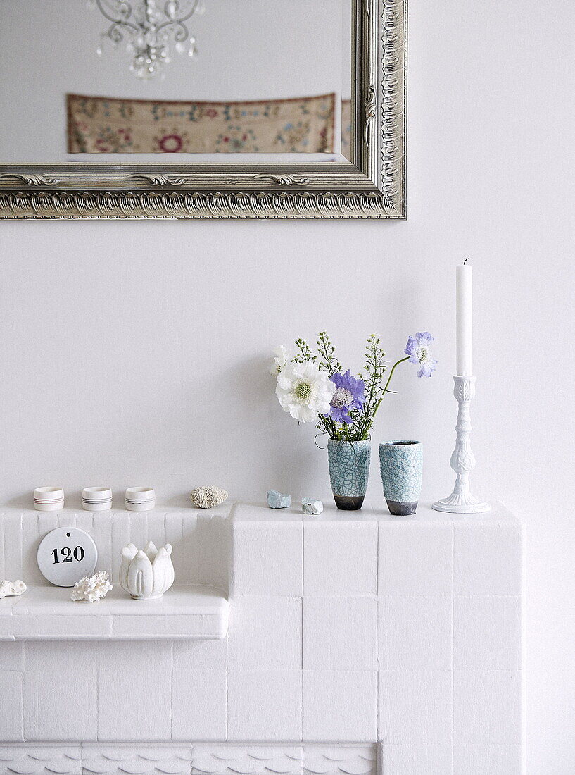 Schnittblumen und Kerze unter silbernem Spiegelrahmen auf gestrichenem Kamin in einem Londoner Haus UK