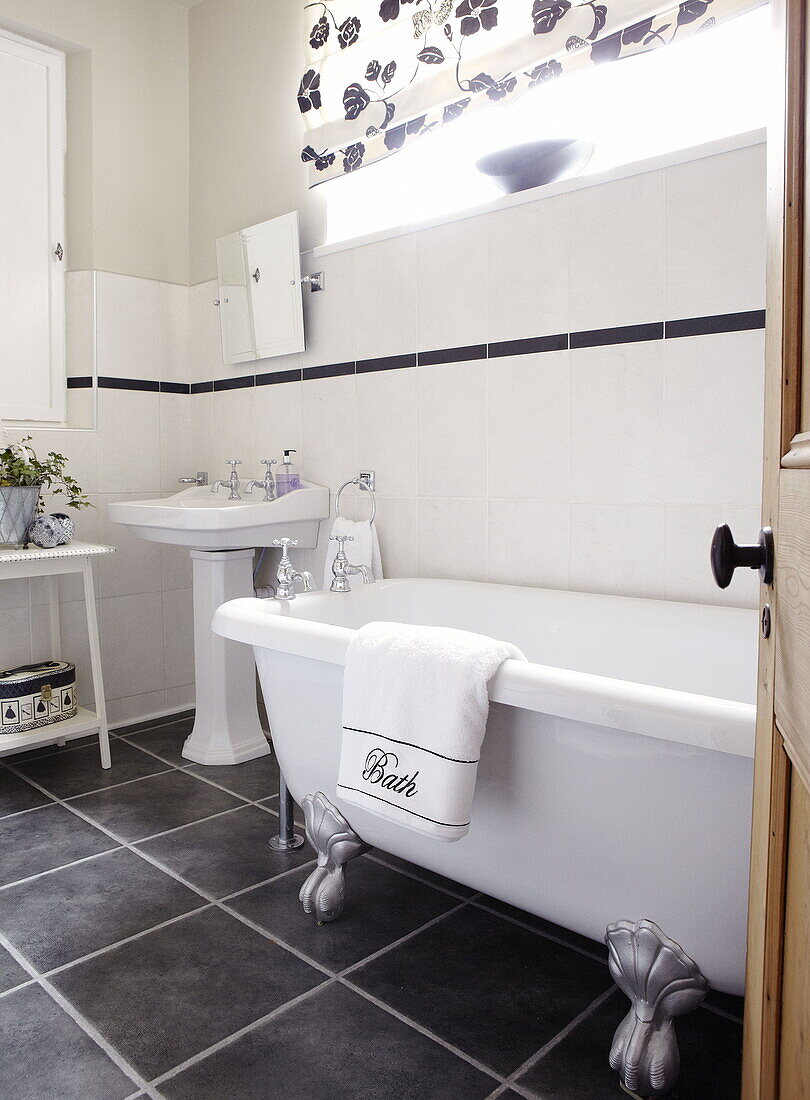 Sockel und freistehende Badewanne im grau gefliesten Badezimmer eines Hauses in Gateshead, Tyne and Wear, England UK