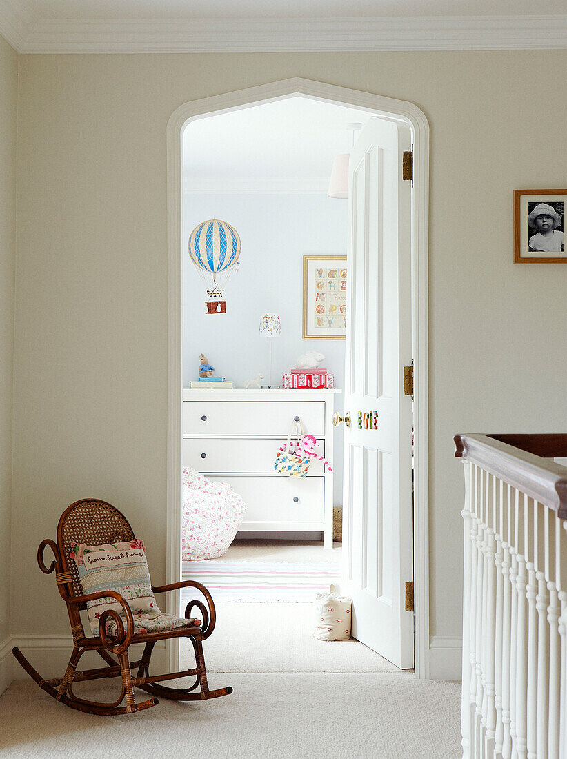 Schaukelstuhl auf dem Treppenabsatz mit Blick durch die Tür zum Kinderzimmer in einem Haus in Oxfordshire, England, Vereinigtes Königreich