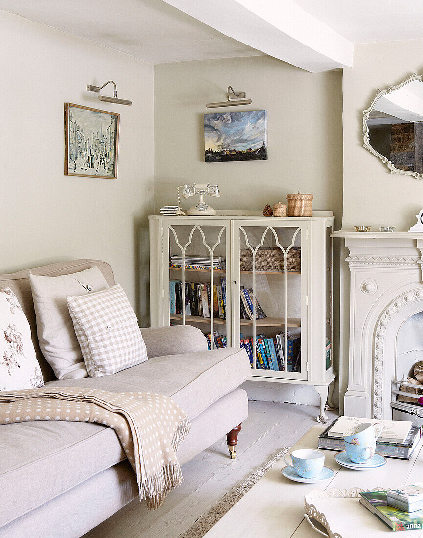 Glasvitrine und Sofa im Wohnzimmer eines Hauses in Oxfordshire, England, UK