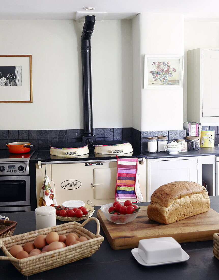Eggs and bread with tomatoes in Oxfordshire farmhouse kitchen with black splashback and cream Aga, England, UK