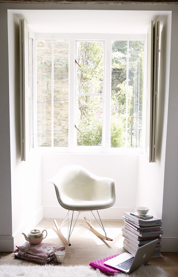 Eames rocker with laptop and books in window of contemporary Oxfordshire cottage, England, UK