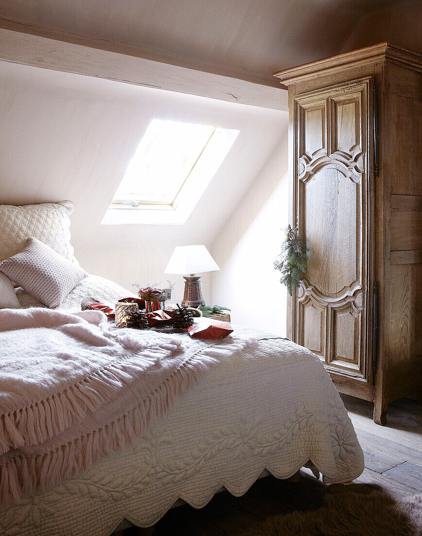 Sunlit attic bedroom with antique wooden wardrobe in festive Oxfordshire home, England, UK