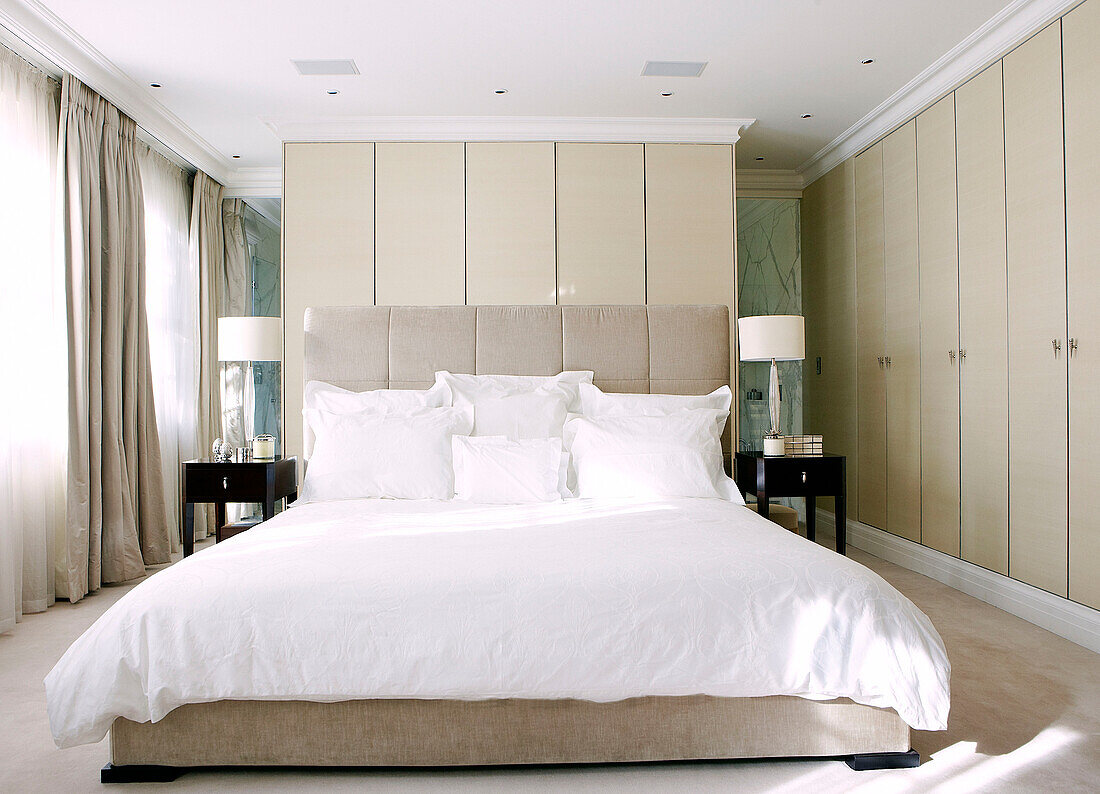 Hauptschlafzimmer mit weißer Bettdecke und passenden Nachttischen aus Dar-Holz in einem Haus in London, England, UK