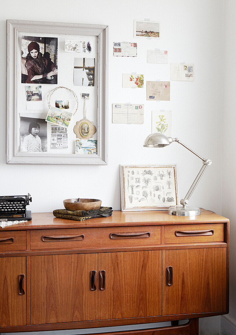 Souvenir postcards and photographs with silver desk lamp on vintage wooden sideboard in Hastings home, East Sussex, UK
