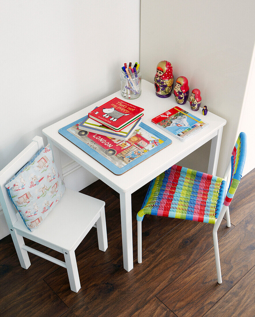 Childs placemat and books with Russian dolls on table with chairs in Greenwich family home, London, UK