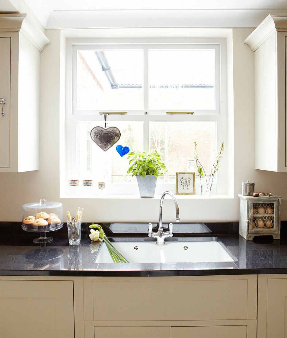 Sunlit window above kitchen sink in Warwickshire home, England, UK