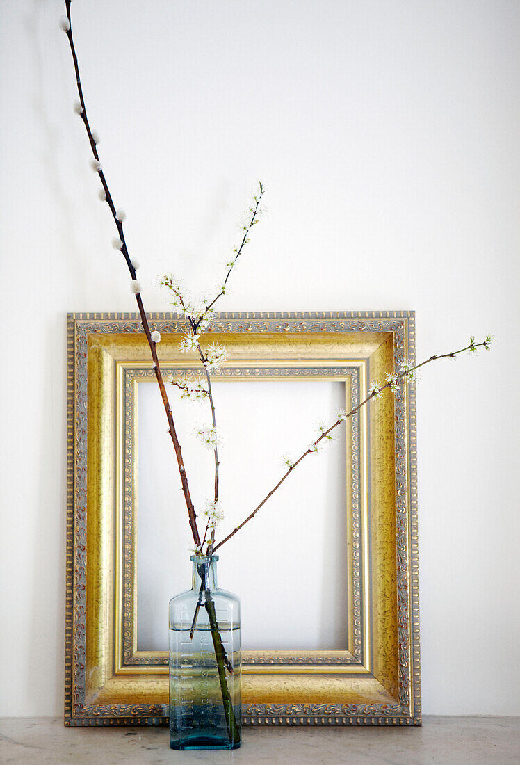 Sprigs of blossom in vase with empty picture frame in Warwickshire home, England, UK