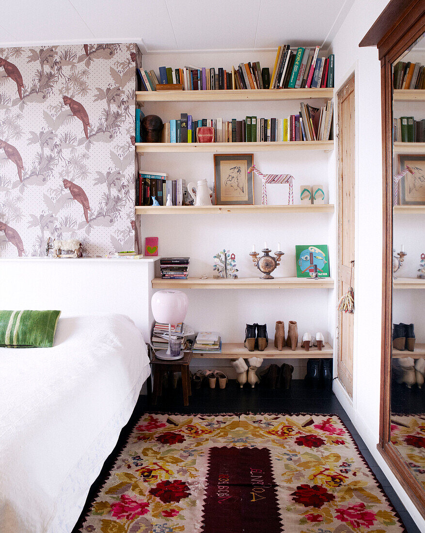 Floral floor rug and bookshelves with shoe storage in bedroom of contemporary home, Amsterdam, Netherlands
