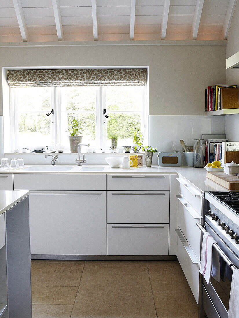 Küchenspüle am Fenster mit Rezeptbüchern und weißen Einbaumöbeln, Oxfordshire, England, UK