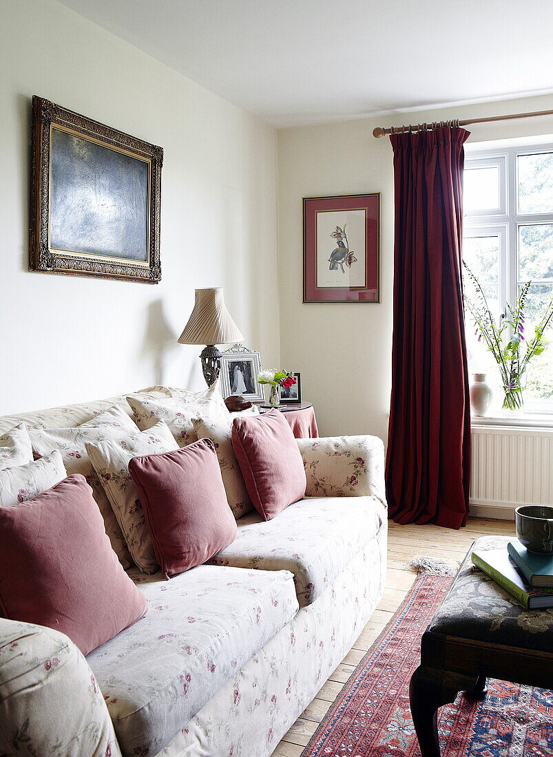 Vergoldetes gerahmtes Kunstwerk über dem Sofa im Wohnzimmer mit roten Vorhängen, Oxfordshire, England, UK