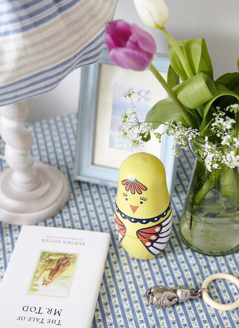 Book and lamp with cut tulips on bedside table in childs room, Oxfordshire, England, UK