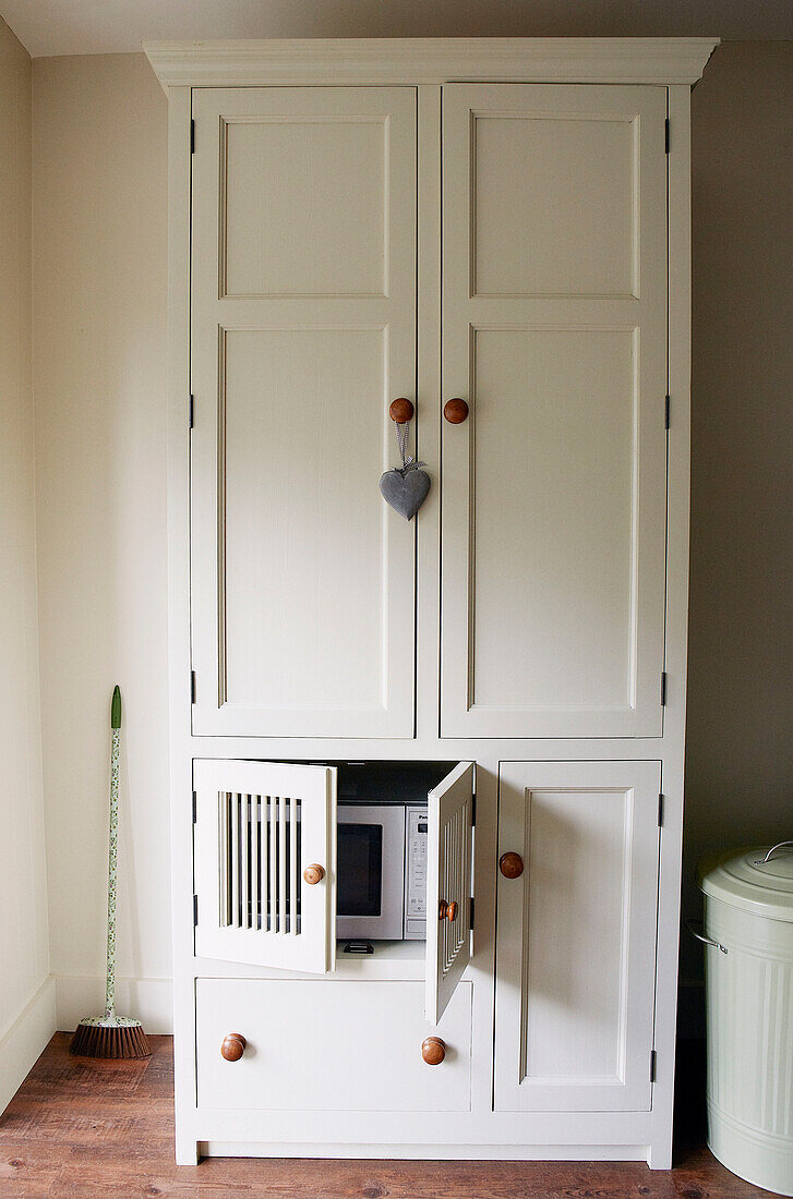 Weiße Küchenkommode mit versteckter Mikrowelle in einem Haus im Norden Londons, England, UK