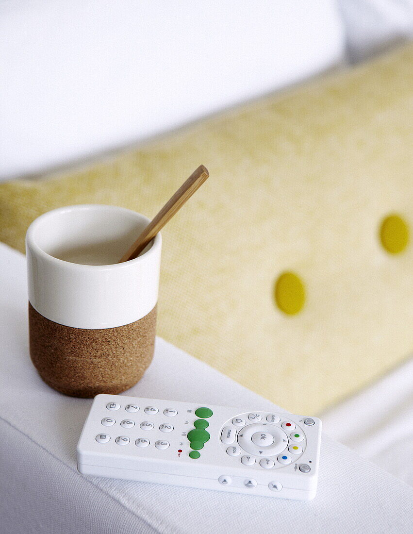 Cup and spoon with remote control on arm of sofa in Bussum home, Netherlands