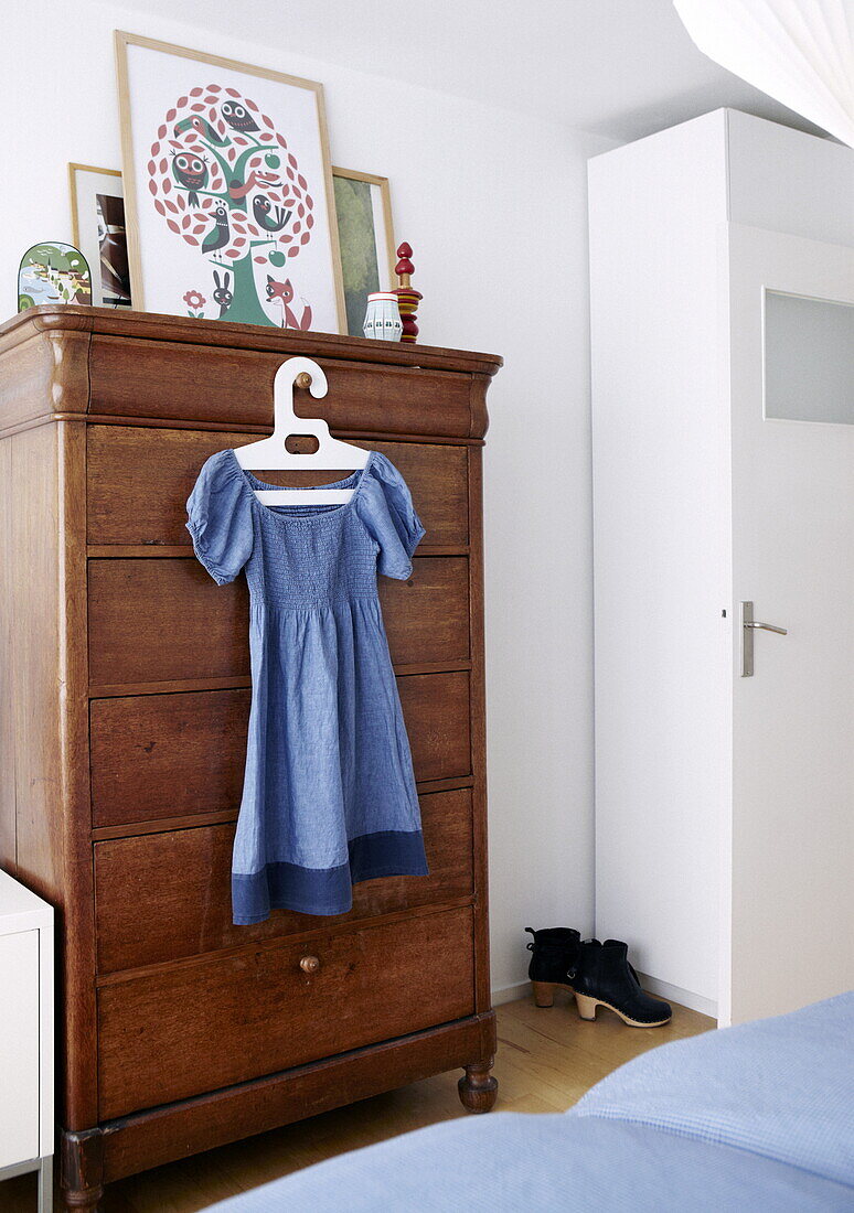 Blaues Kleid hängt an einem antiken hölzernen Tallboy im Schlafzimmer eines Hauses in Bussum, Niederlande