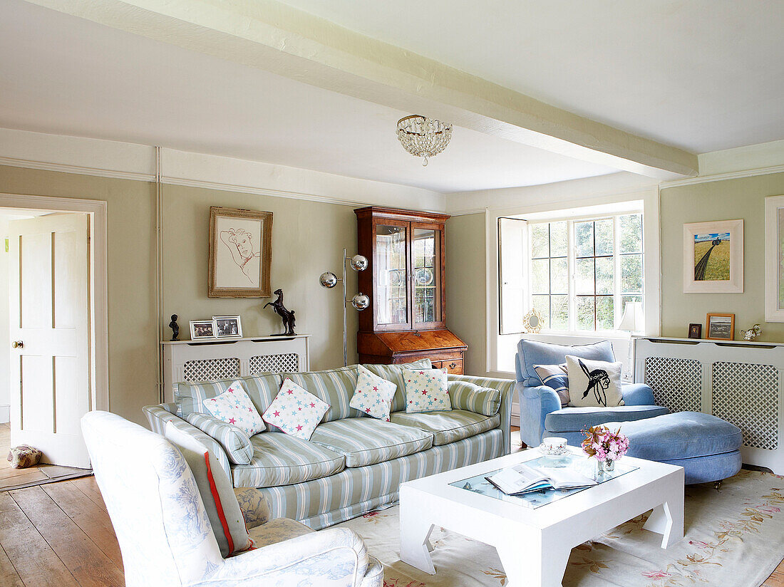 Striped sofa and armchair with footstool in living room of Oxfordshire farmhouse England UK