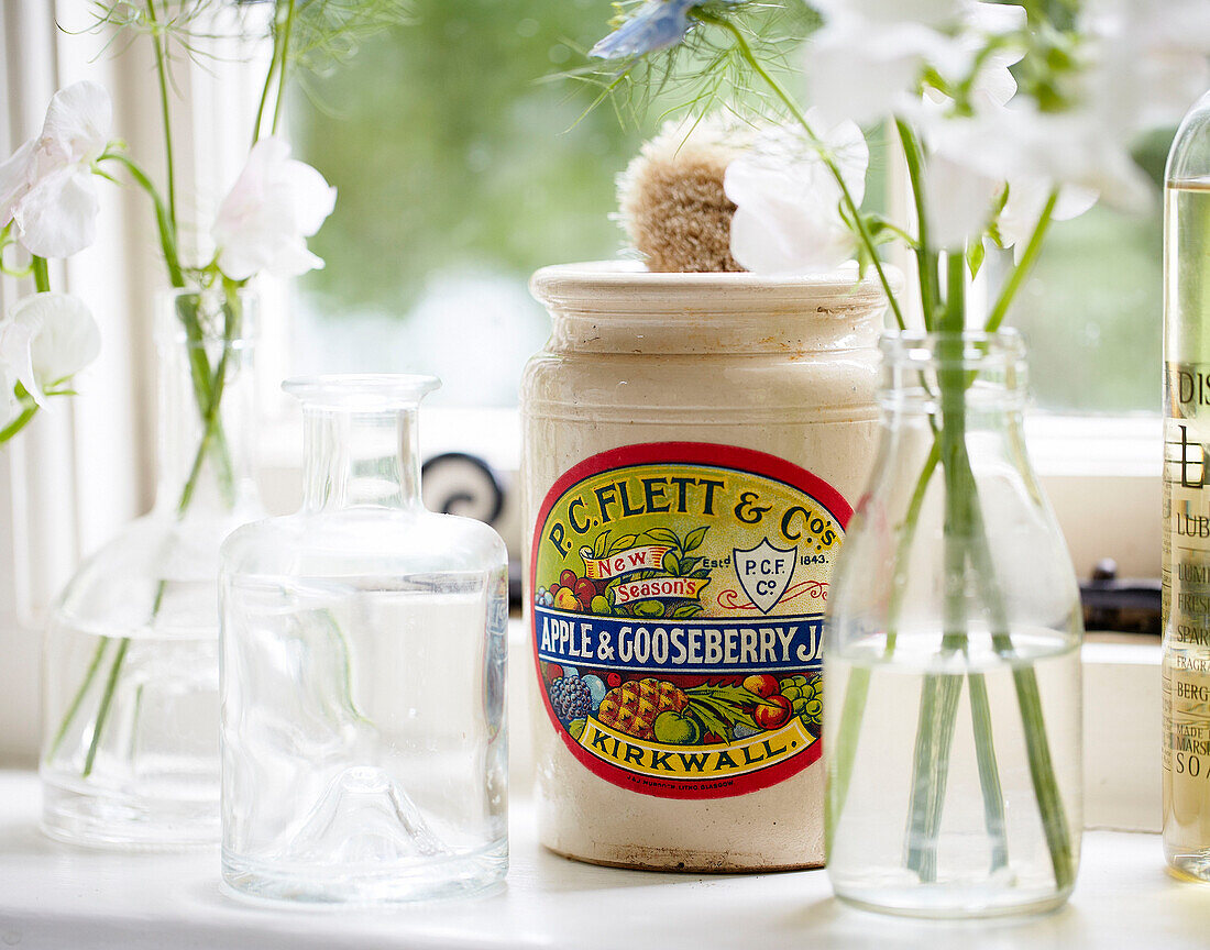 White cut flowers and vintage jar on windowsill of Surrey farmhouse kitchen England UK