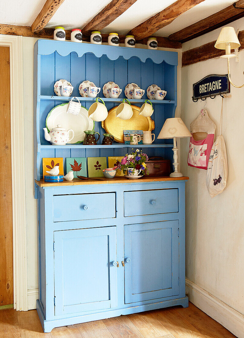 Chinaware on light blue painted kitchen dresser in Surrey farmhouse kitchen England UK