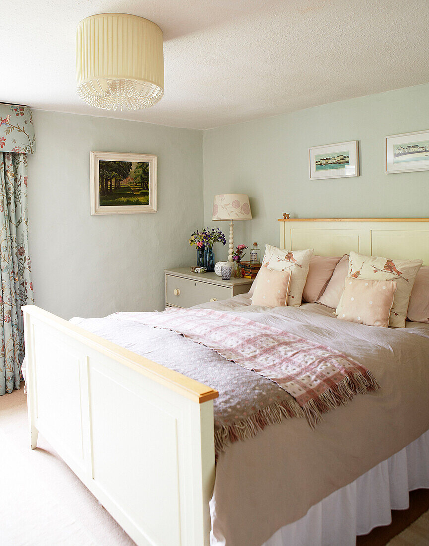 Doppelbett mit rosa Kissen im pastellgrünen Schlafzimmer eines Bauernhauses in Surrey England UK