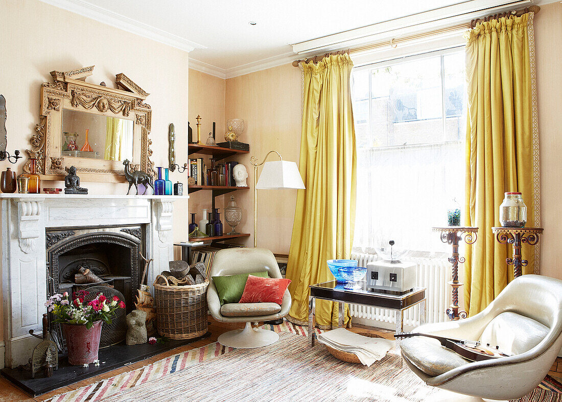 Zwei Sessel im Retrostil und goldene Vorhänge im Wohnzimmer eines Londoner Stadthauses England UK