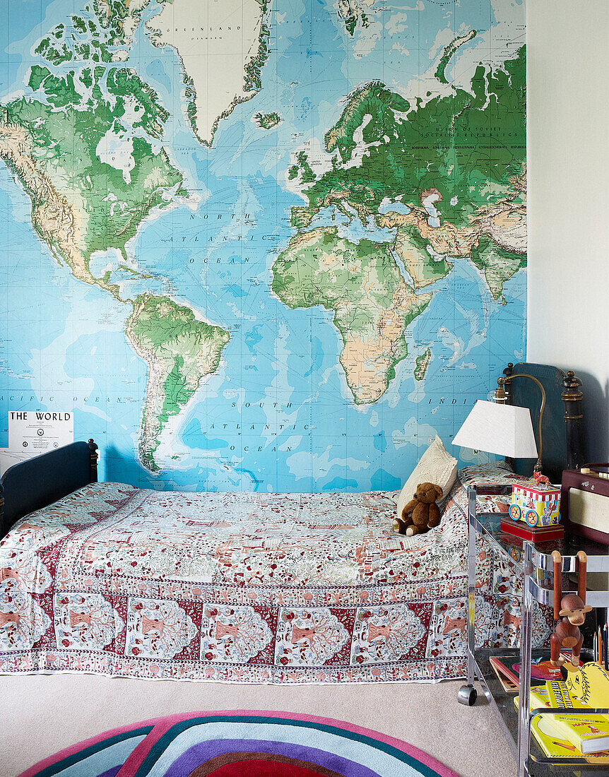 World map above single bed in boy's room of London townhouse England UK