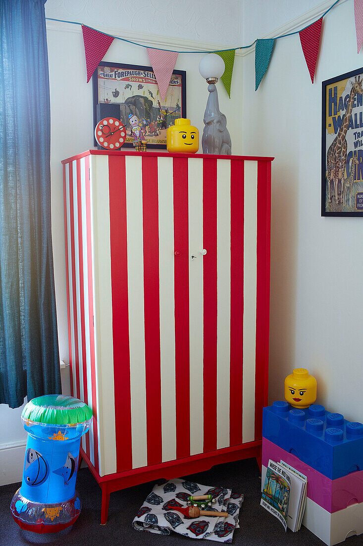 Red and white striped wardrobe with bunting and toys in child's room of family home Margate Kent England UK