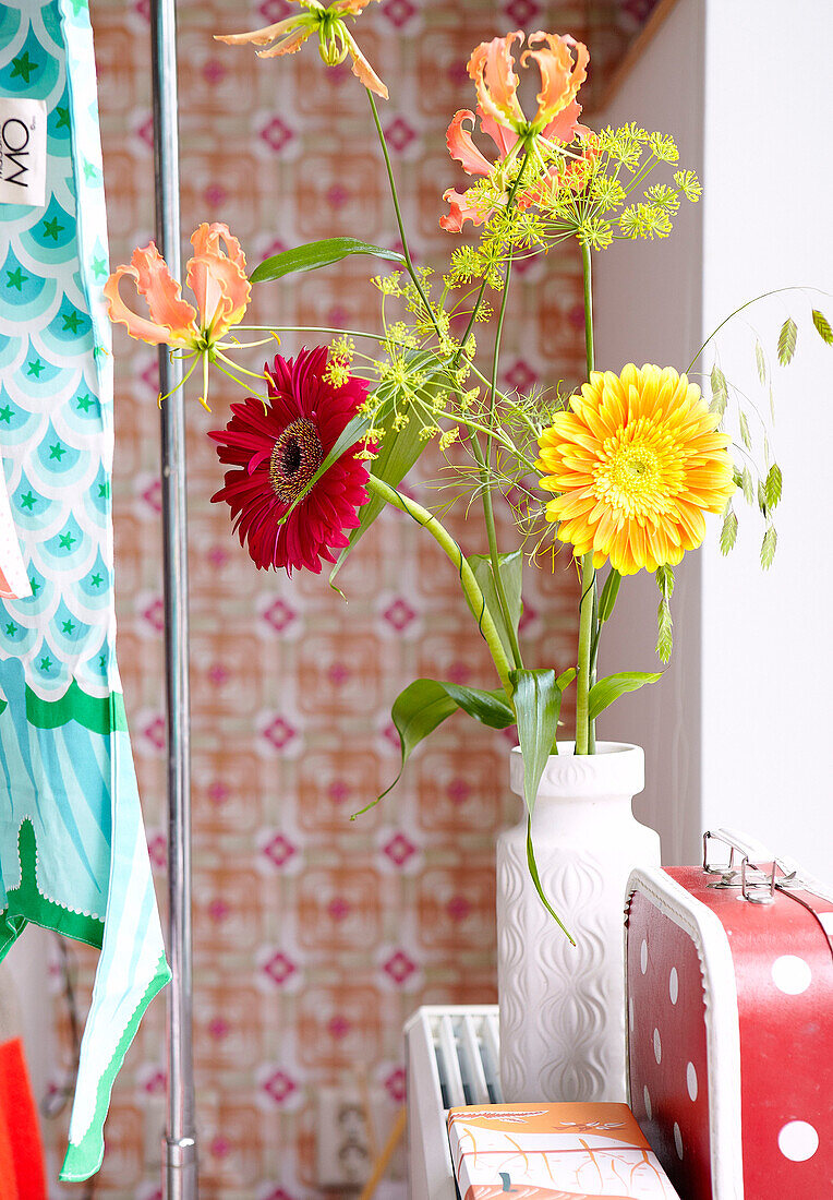 Red and yellow gerbera in vase with spotty suitcase in Mattenbiesstraat home, Netherlands