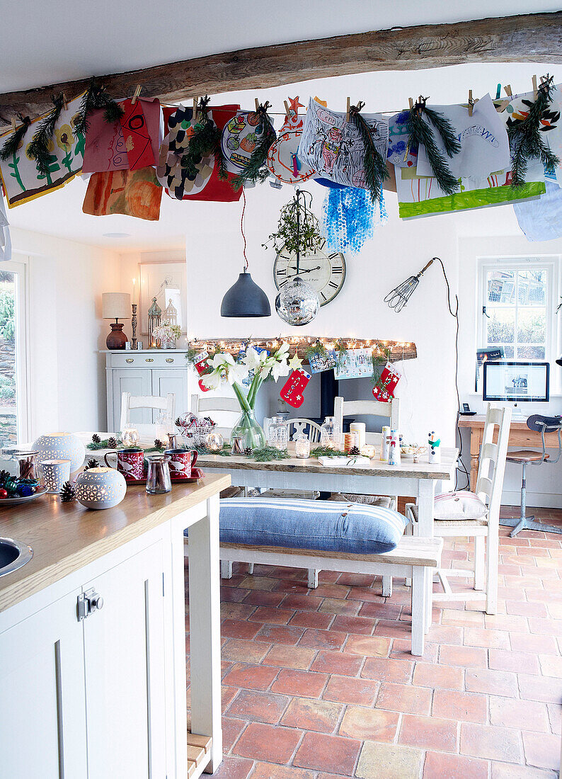 Child's drawings hang under beamed ceiling in open plan kitchen of Devonshire farmhouse UK