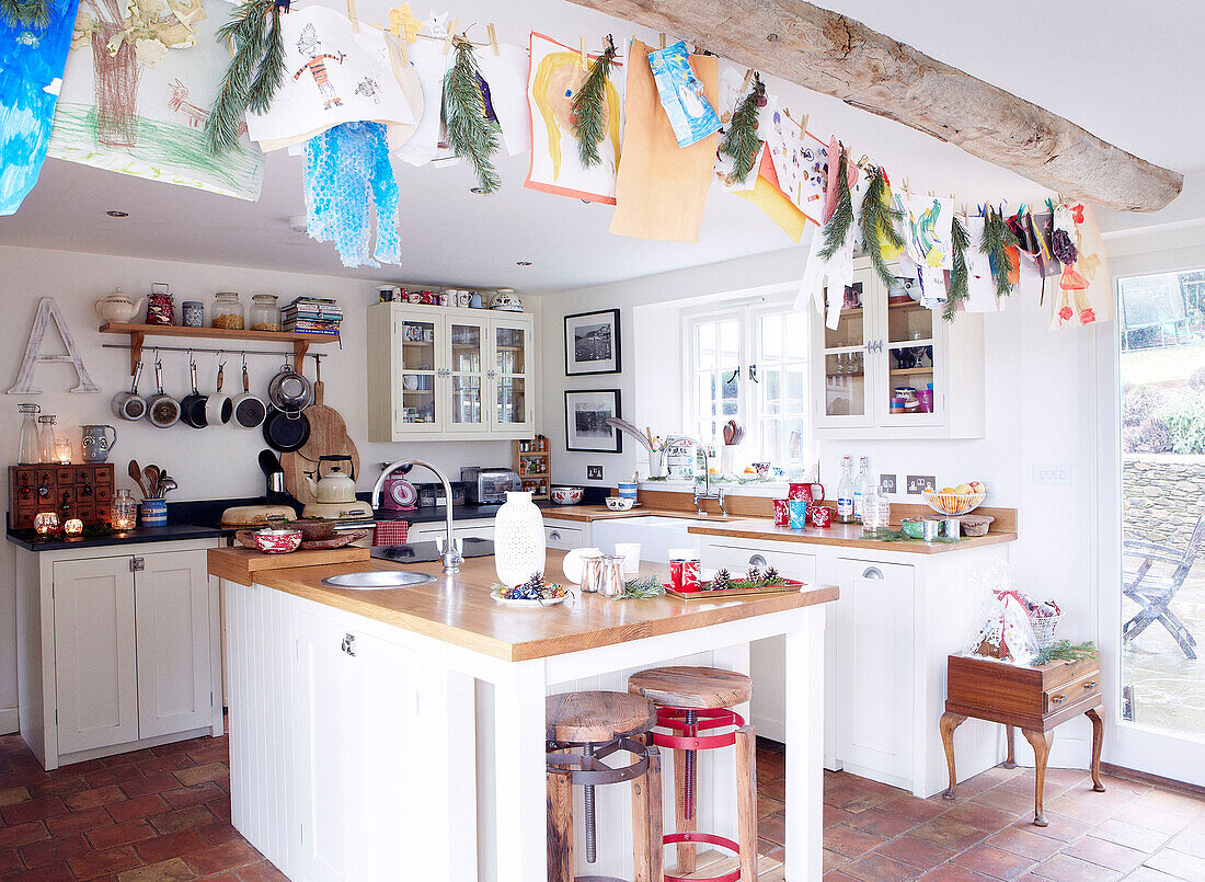 Kinderzeichnungen hängen von Deckenbalken in offener Küche eines Bauernhauses in Devonshire, UK