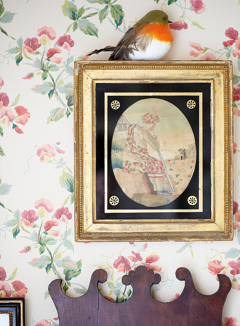 Robin on gilt framed artwork with floral wallpaper in Oxfordshire country house England UK