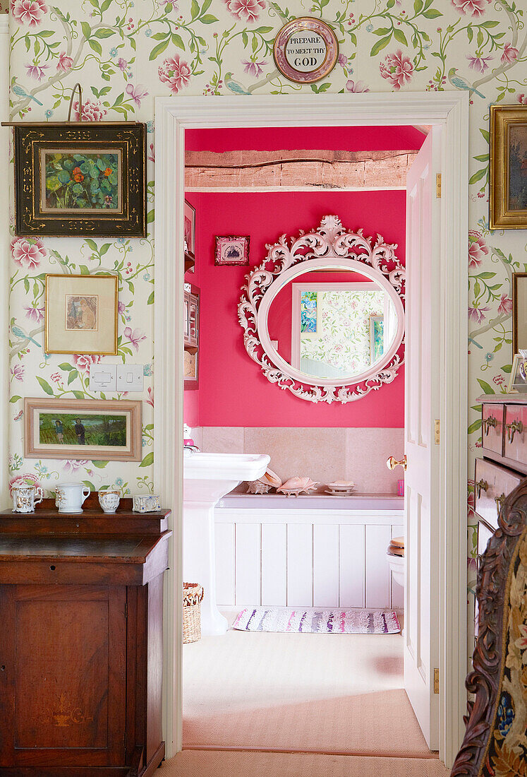 Blick durch die Tür zu einem rosafarbenen Badezimmer in einem Landhaus in Oxfordshire England UK