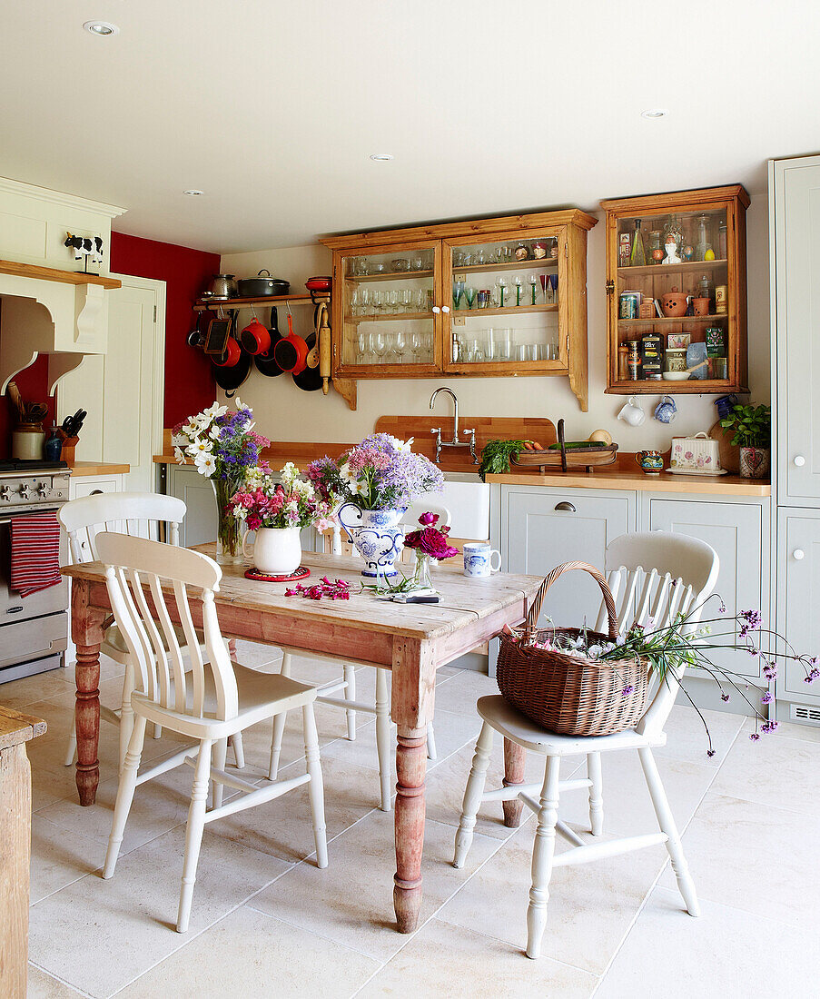 Cut flowers and basket on painted kitchen chairs on table in rural Oxfordshire cottage England UK