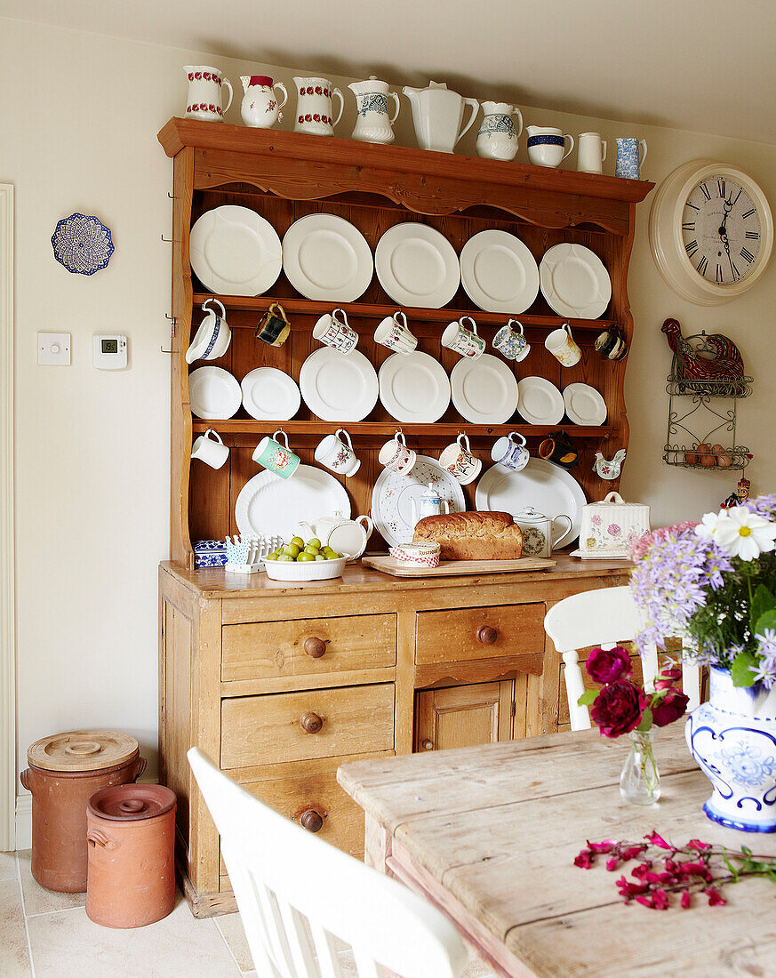 Teller und Tassen auf einer hölzernen Küchenkommode in einem Cottage in Oxfordshire, England