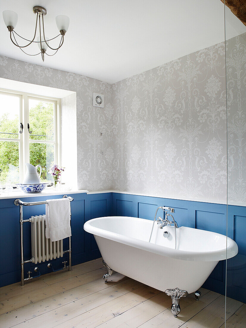 Freistehende Badewanne im blau getäfelten Badezimmer eines Cottage in Oxfordshire, England, UK