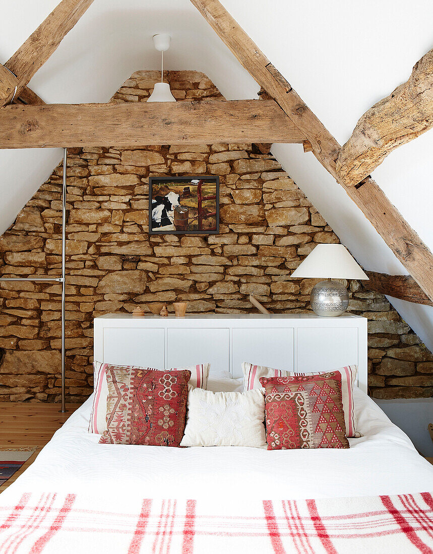 Schlafzimmer mit Dachbalken und freiliegender Steinmauer in einem Landhaus in Oxfordshire England UK