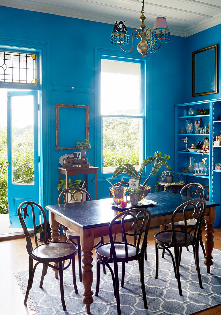 Holztisch und Stühle in einem hellblauen Esszimmer mit offener Hintertür in einem Haus in Auckland auf der Nordinsel Neuseelands