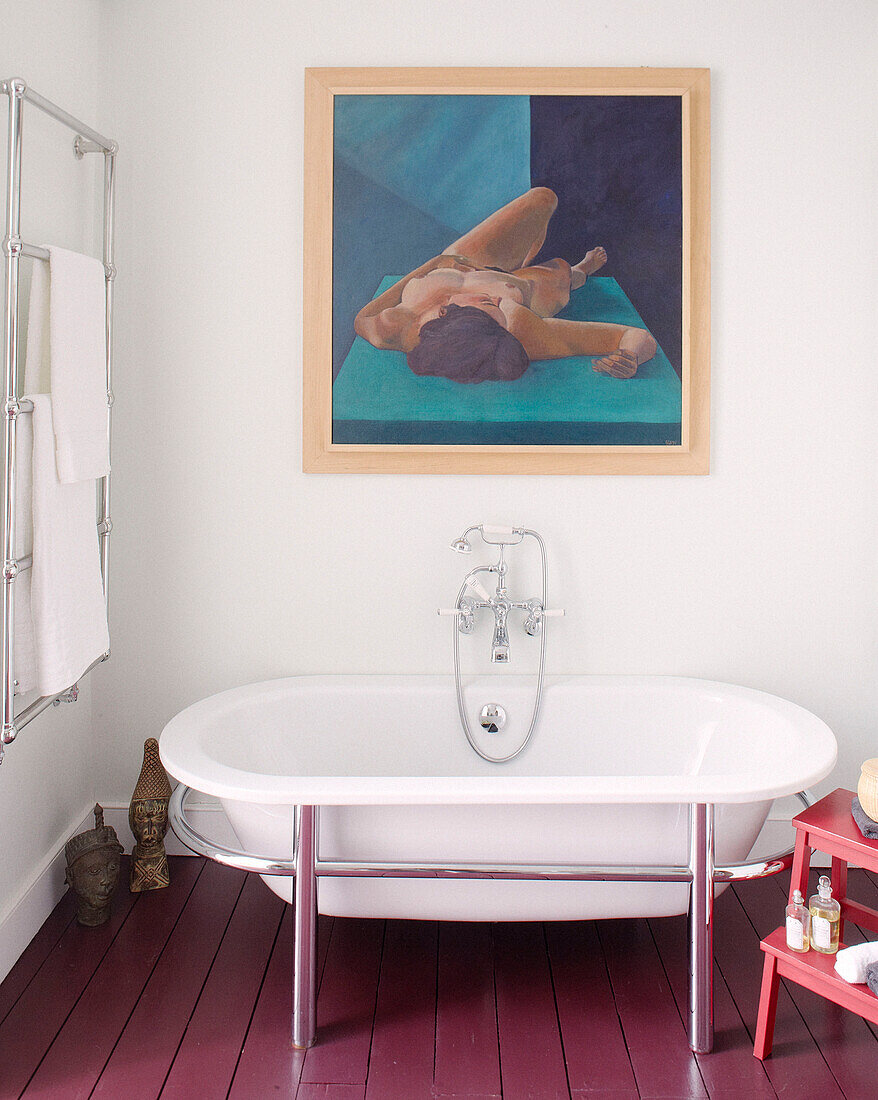 Freistehende Badewanne unter einem Kunstwerk mit wandmontiertem Heizkörper in einem Haus in Notting Hill, West London, Großbritannien