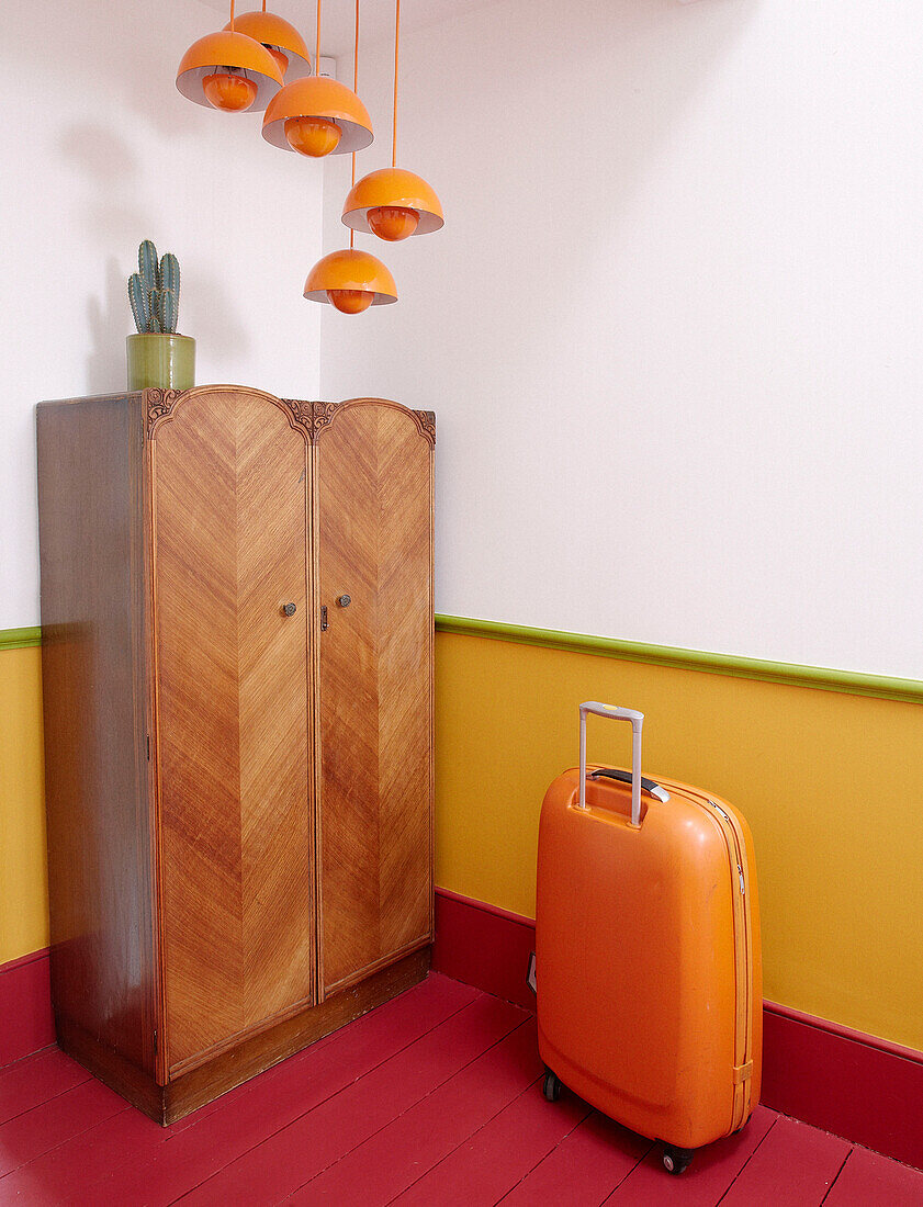 orange suitcase and lights with vintage wardrobe in Notting Hill home West London UK