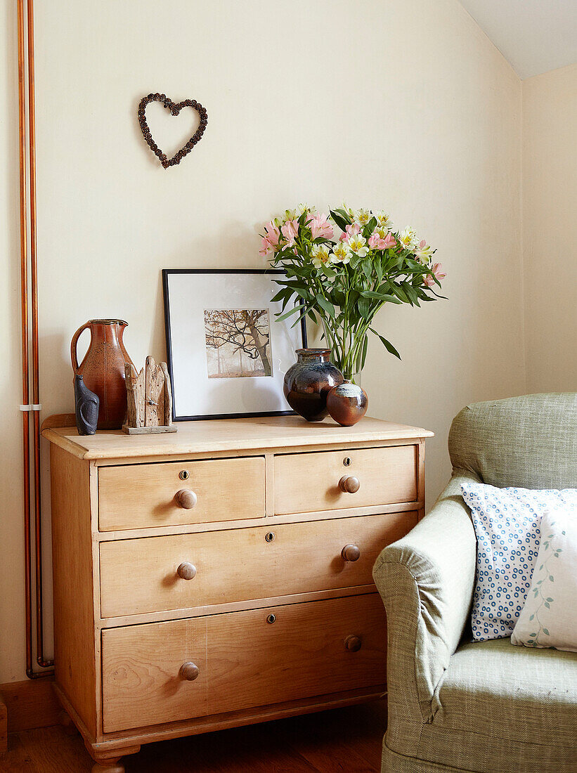 Wooden chest of drawers with armchair in bedroom of Derbyshire farmhouse England UK