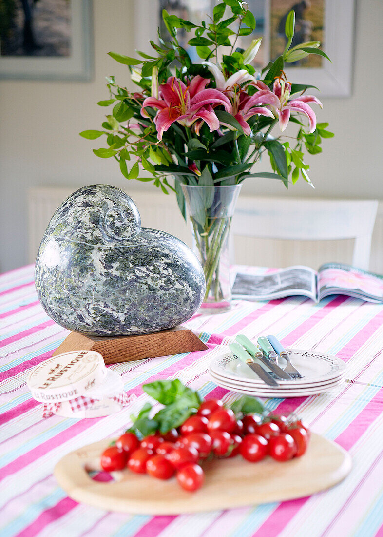 Heart shaped ornament with cut lilies and cherry tomatoes on kitchen table in Nottinghamshire barn conversion England UK