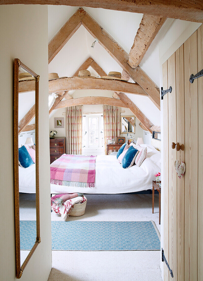 View through doorway to beamed attic bedroom of Nottinghamshire barn conversion England UK