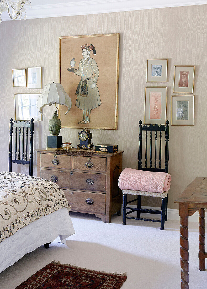 Orientalisches Kunstwerk mit passenden Stühlen und Holzkommode im Schlafzimmer eines traditionellen Landhauses an den walisischen Grenzen, UK
