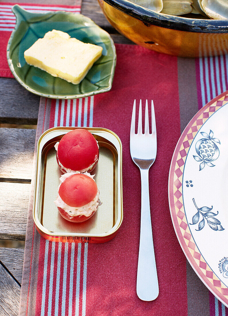 Stuffed tomatoes and leaf-shaped butter dish at place setting on Brittany table France