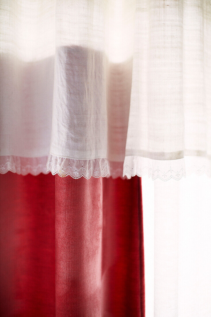 White muslin with lace trimming with red velvet curtain in Brittany home France